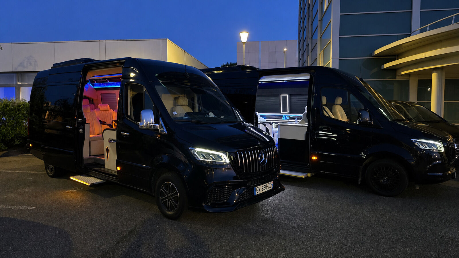 Deux Mercedes Sprinter VIP Paris noirs stationnés de nuit devant un hôtel — chauffeur privé haut de gamme