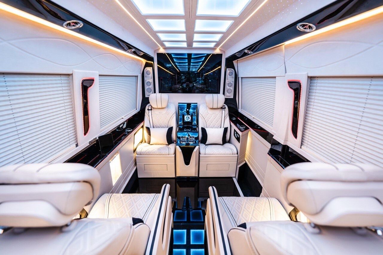 Intérieur Sprinter VIP Paris 7 passagers — lounge avec bar central et sièges capitaine cuir blanc